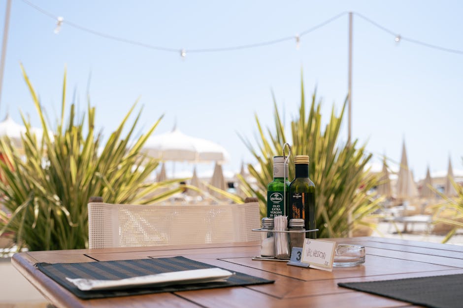 A serene outdoor dining table setup in Milano Marittima featuring olive oil and vinegar amidst lush plants.