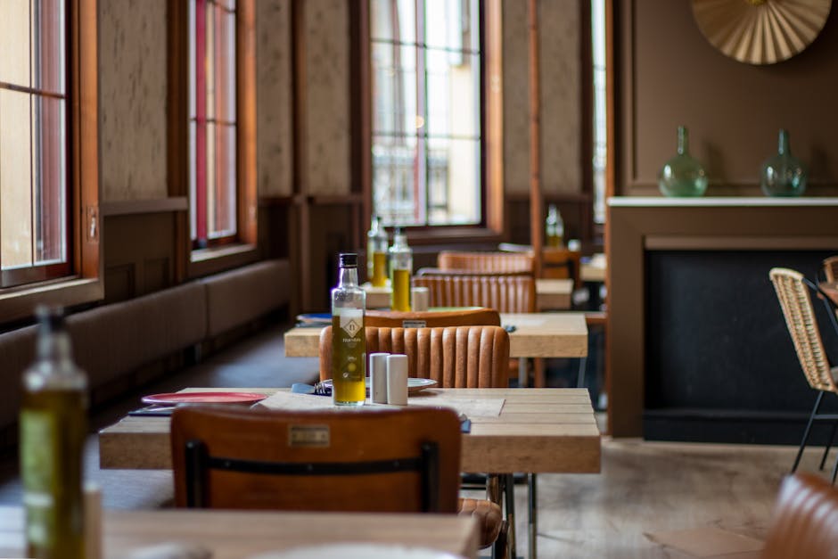 Inviting restaurant interior featuring wooden tables with olive oil bottles and leather chairs in focus.